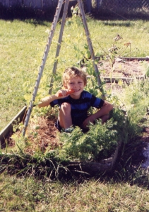 Sean in a garden pea tee-pee eating a carrot thinned from the edging. 