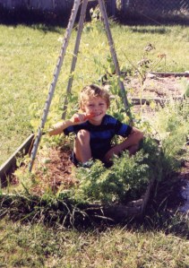 Sean in a garden pea tee-pee eating a carrot thinned from the edging. 